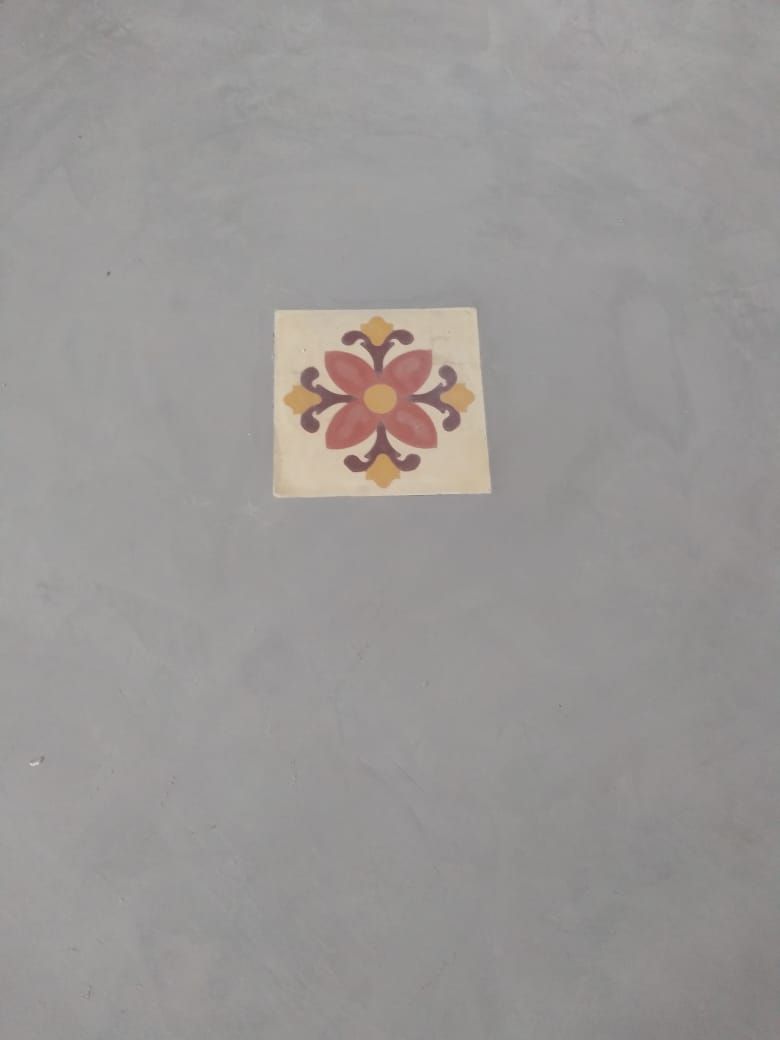 Detalhe de ladrilho hidráulico floral embutido em piso de cimento queimado