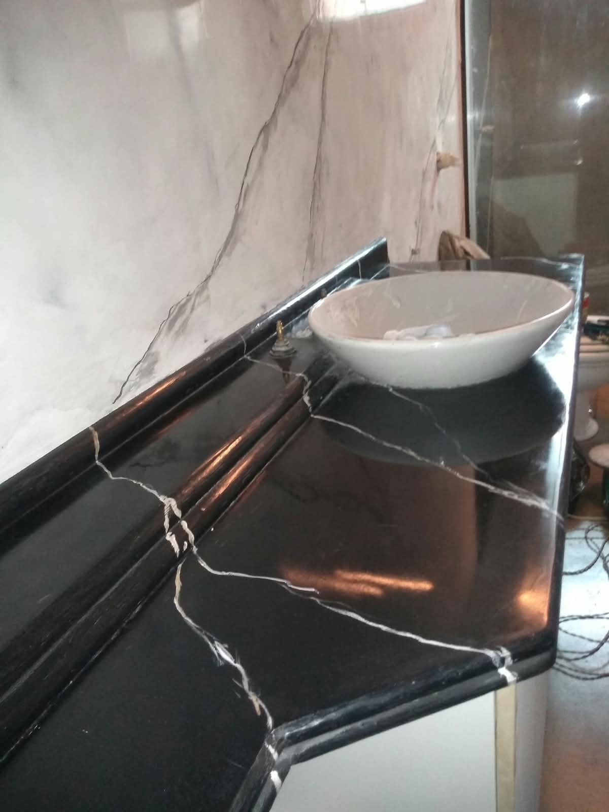 Close de bancada em marmorato preto com veios brancos em relevo, obra do Shamir Marmorato