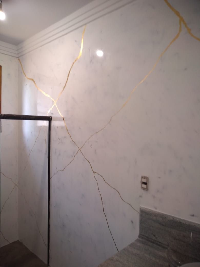Detalhe de parede em marmorato branco com veios dourados contínuos