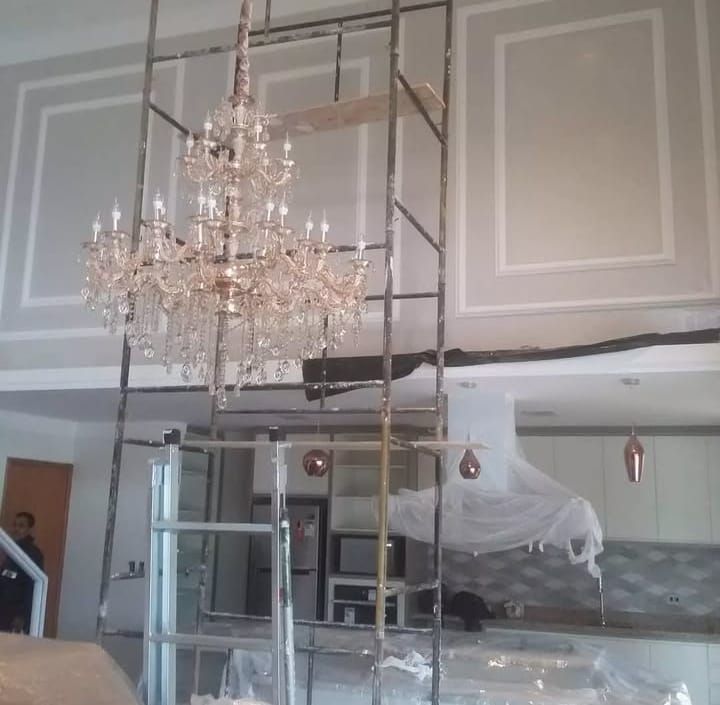 Sala de pé-direito duplo em obra de alto padrão, com lustre de cristal e molduras